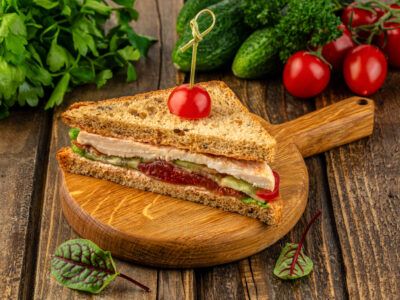 Сендвич с курицей, овощами и листьями салатов